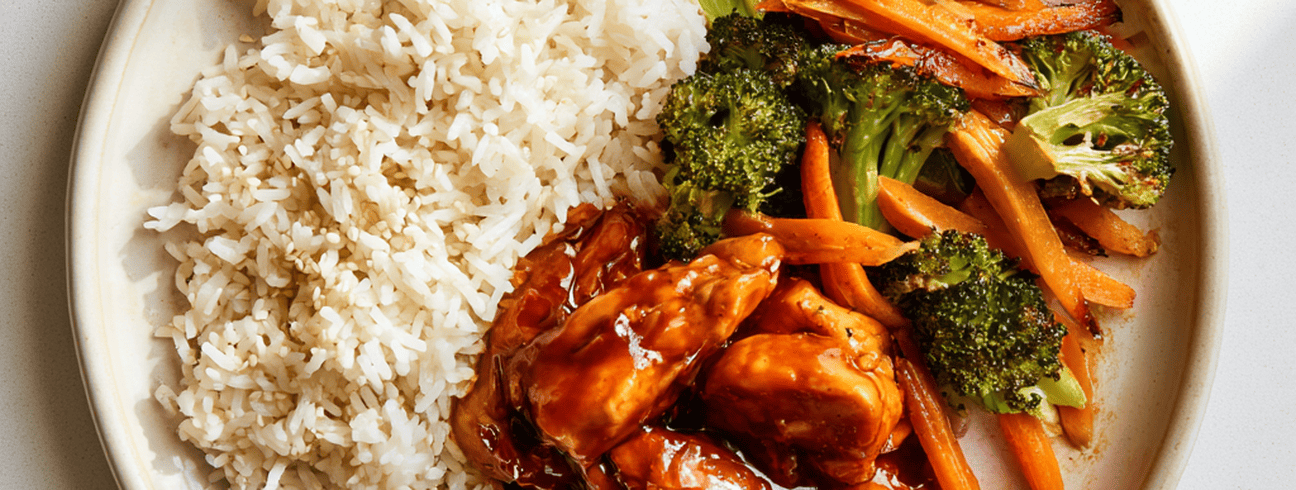 Assiette vue de dessus avec riz, brocolis, carottes et morceaux de poulet grillé, illustrant un repas équilibré