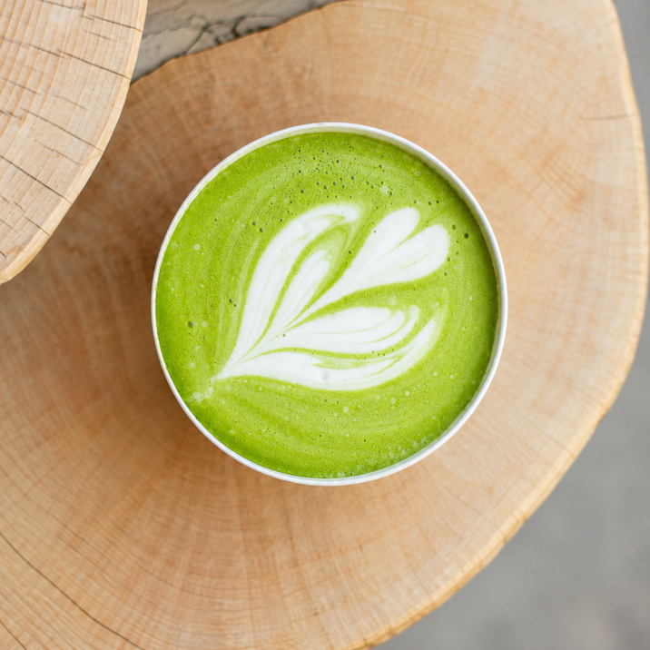 Matcha latte avec une belle mise en situation servi dans une tasse en céramique posée sur un plateau en bois clair