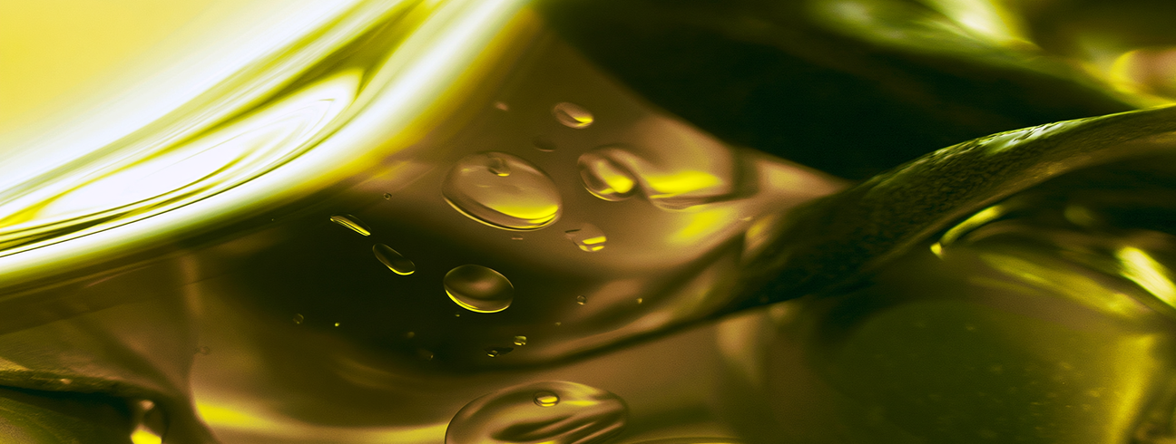 Gros plan sur un filet d’huile d’olive et ses gouttelettes, avec une feuille d’olivier, en écho au rôle de l’huile d’olive comme support des gouttes de vitamine D3, Therascience